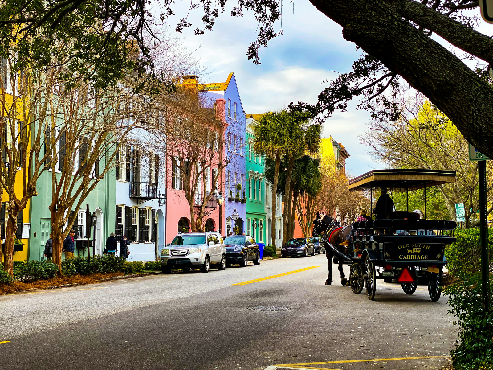 Colorful Charleston row houses with a horse-drawn carriage on a cobblestone street